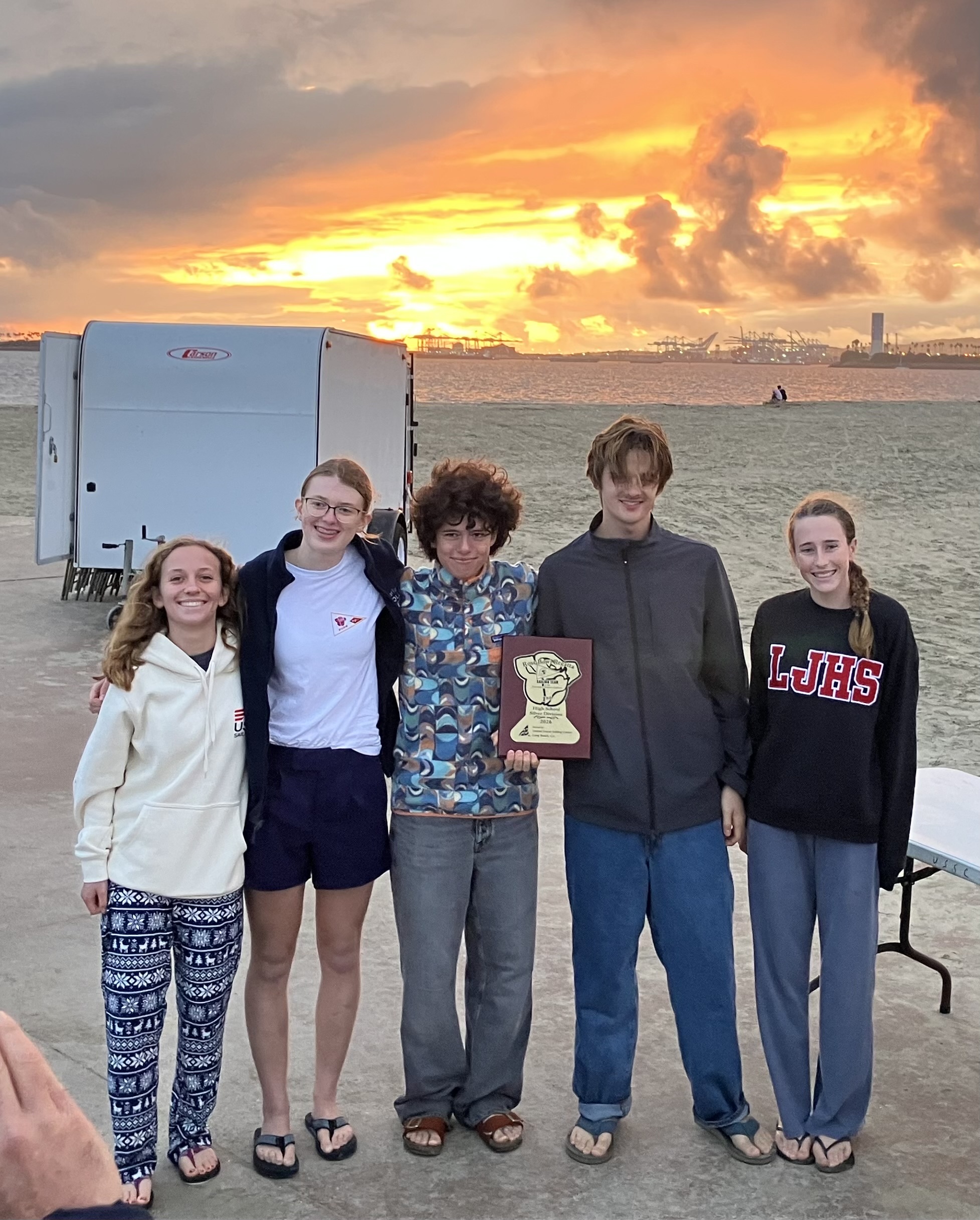 Team posing for a group photo after receiving their first place Rose Bowl prize with an impressive sunset in the foreground.